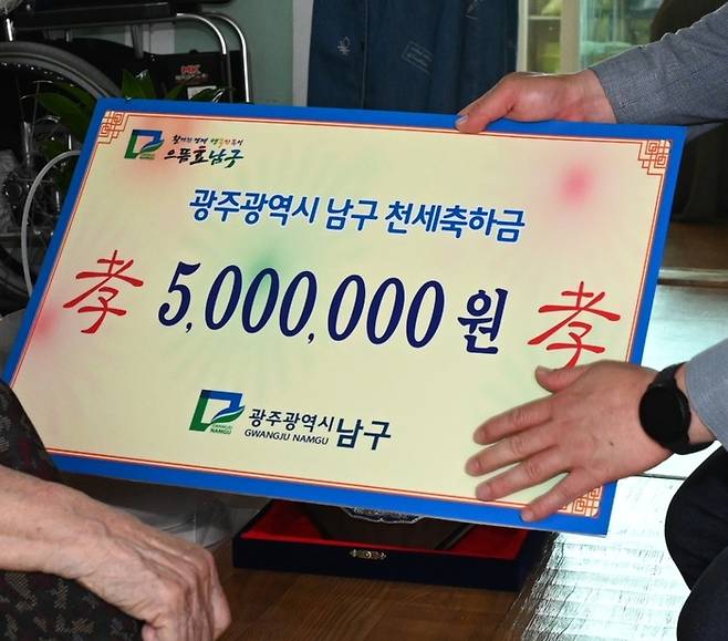 지난 3일 광주광역시 남구가 관내 최고령인 111세 어르신에게 ‘천세축하금’ 500만원과 축하패, 20만원 상당의 가족사진 촬영권을 전달하고 있다.  광주 남구청 제공