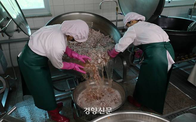 급식 조리사 두 명이 제육덮밥을 하기 위해 돼지고기를 삶은 물을 버리고 있다. 솥이 워낙 크고 무거워 두 명이서 하지 않으면 작업을 하기 어렵다. 서울특별시교육청 학교보건진흥원에 따르면 2019년 급식실에서 발생한 상해 중 가장 많은 것은 화상(31.1%)이었고, 상해 부위 중 가장 많은 부위는 손(34.4%)이었다.