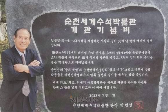 박병선 순천세계수석박물관장이 박물관 정문 앞에 있는 기념탑 앞에서 활짝 웃고 있다.