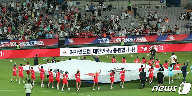 8일 서울 마포구 상암동 서울월드컵경기장에서 열린 2023 FIFA 호주‧뉴질랜드 여자월드컵 출정식에서 선수들이 대형 태극기를 들고 팬들을 향해 손을 흔들고 있다. 2023.7.8/뉴스1 ⓒ News1 허경 기자