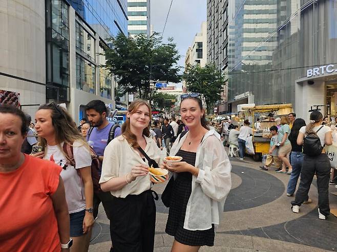 스위스에서 온 대학생 패트리샤(25)와 안나(22)가 사진 촬영에 응해줬습니다. 떡볶이와 새우튀김을 먹고 있던 이들은&nbsp;“스위스 물가에 비하면 합리적인 가격이라고 생각한다”고 했습니다. 떡볶이는 맛있다고 합니다. 조성민 기자