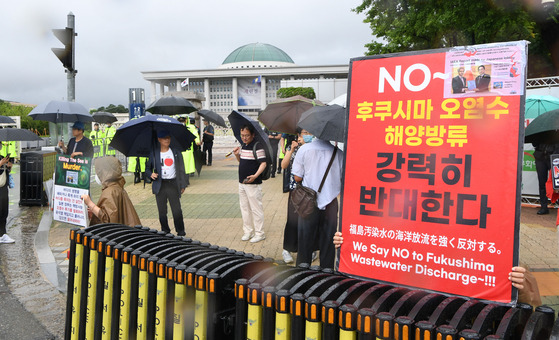 Members of civic groups protest against the Japanese plan to release its treated radioactive water into the sea in front of the National Assembly in Seoul on Sunday as the chief of the International Atomic Energy Agency meets with members of the liberal Democratic Party. [KIM SEONG-RYONG]