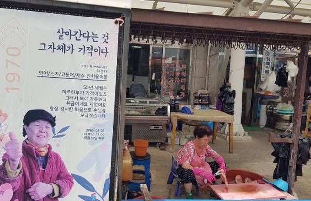 울진바지게시장에서 수산물을 파는 한 상인이 생선을 손질하고 있다. 점포 앞에 가게를 소개하는 입간판이 보인다. 울진=김정혜 기자