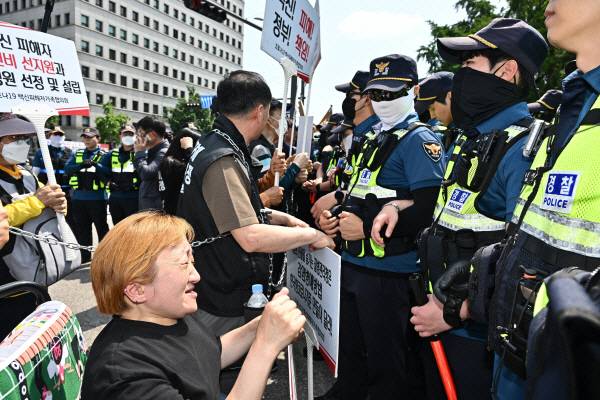 몸을 쇠사슬로 묶은 코로나19백신피해자가족협의회 회원들이 지난 5월 31일 국회 앞에서 김진표 국회의장과 면담을 요구하며 경찰과 대치하고 있다. 김정록 기자