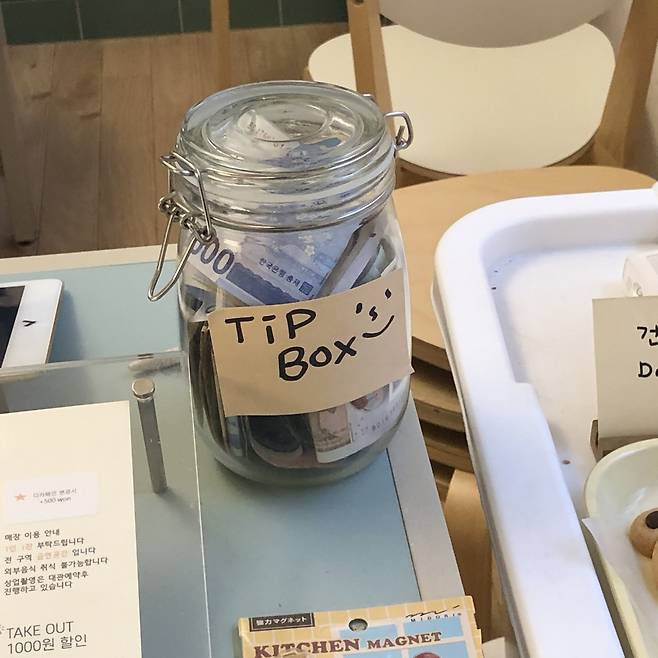 A glass jar labeled "Tip Box" is placed on a counter at a cafe. (Twitter post)