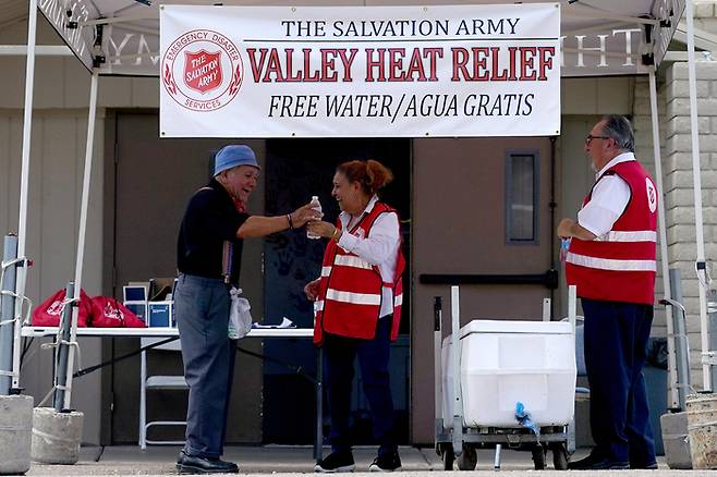 11알(현지시간) 미국 애리조나주 피닉스에서 자원봉사자들이 생수를 시민들에게 나눠주고 있다. 피닉스는 11일 연속 43도 이상의 폭염을 기록했다. AP연합뉴스