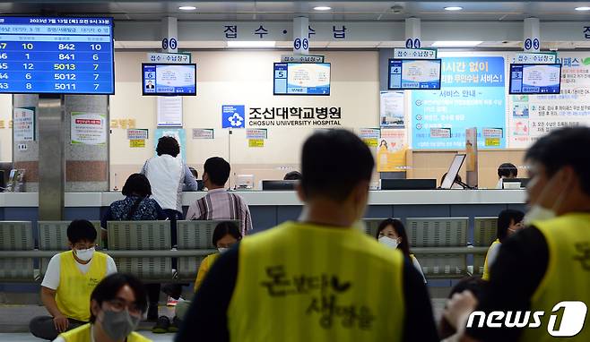 전국보건의료산업노동조합이 총파업에 돌입한 13일 오전 광주 동구 조선대학교 병원 로비에서 노조원들이 농성을 하고 있는 가운데 환자들이 진료를 위해 대기하고 있다. 2023.7.13/뉴스1 ⓒ News1 이승현 기자