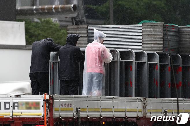 서울 전역에 호우주의보가 발효된 13일 서울 시내에서 화물운송 직원들이 내리는 비를 맞고 있다. 2023.7.13/뉴스1 ⓒ News1 김민지 기자