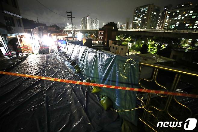 13일 집중 호우로 도로 축대가 무너져 내린 서대문구 홍제천 인근 지반에 빗물이 들어가는 것을 막는 방수포가 씌워져 있다. 이날 오후 6시34분쯤 발생한 이 사고로 40여명이 긴급 대피했다. 2023.7.13/뉴스1 ⓒ News1 김민지 기자