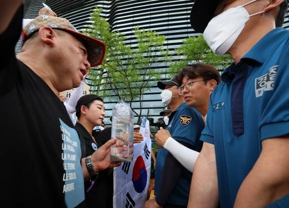 촛불연대 회원들이 지난 8일 오후 서울 종로구 일본대사관 앞에서 직접 후쿠시마 원전 인근 해상에서 떠온 바닷물을 일본대사관 측에 전달하려다 경찰에 가로막히고 있다. 가수 리아(왼쪽에서 두 번째). /연합뉴스