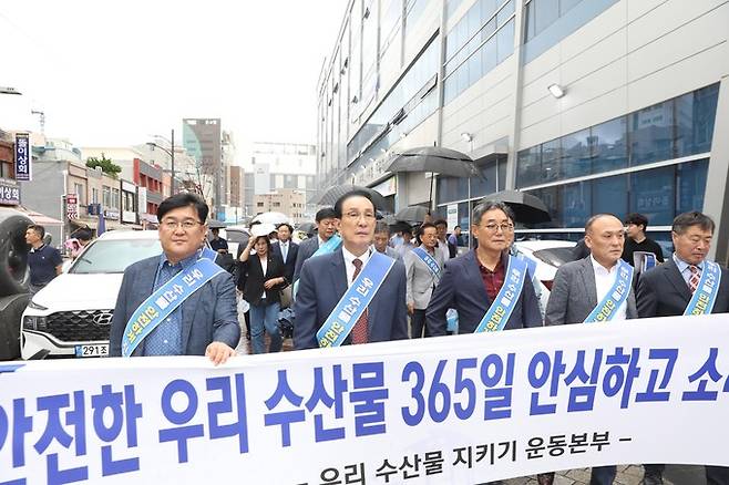 우리 수산물 지키기 운동본부가 14일 부산시수협 자갈치위판장에서 ‘수산물 지키기 릴레이 캠페인’을 개최한 가운데 노동진 수협중앙회장(왼쪽 두번째)이 일본 원전 오염수 방류로 위축된 수산물 소비를 독려하고 수산물이 안전하게 관리되고 있단 사실을 시민에게 홍보하기 위해 가두 행진을 하고 있다.