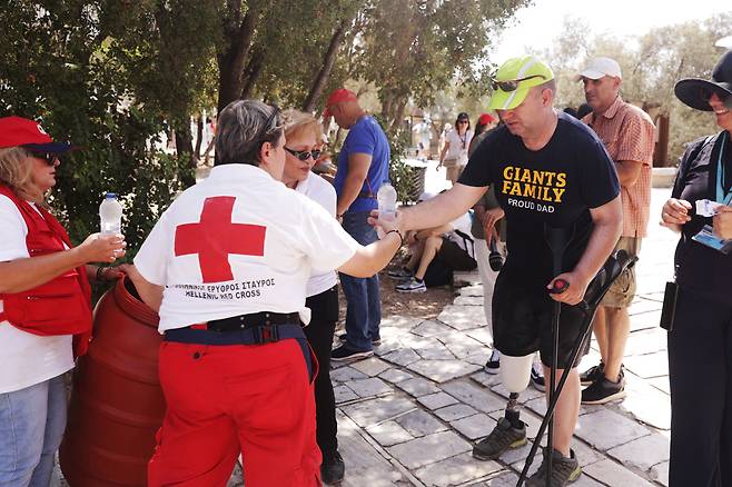 아크로폴리스 앞에서 관광객들에게 물을 나눠주고 있는 그리스 적십자사 요원들. /로이터 연합뉴스