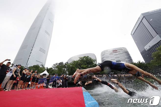 16일 오전 서울 송파구 롯데월드타워 일대에서 열린 '2023 롯데 아쿠아슬론 대회'에 출전한 참가자들이 석촌호수에서 수영하고 있다. 2023. 07. 16 ⓒ News1 신웅수 기자