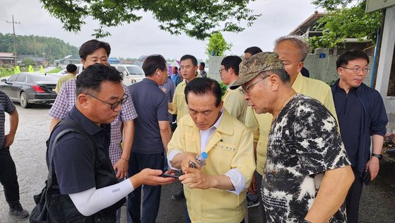 16일 충남 논산 성동면 금강 제방 일부가 유실되자 마을회관에 모인 우곤1리 주민들이 백성현 논산시장과 현장 사진을 확인하고 있다. 신진호 기자