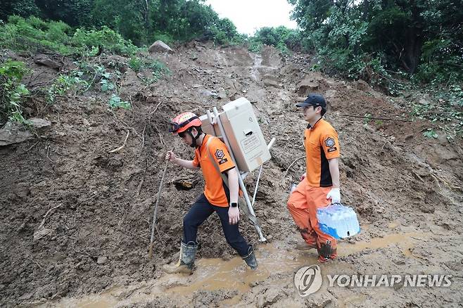 '산사태 현장으로' (예천=연합뉴스) 윤관식 기자 = 16일 오전 경북 예천군 백석리에서 산사태 현장으로 가는 길목이 산사태로 유실돼 차량 진입이 어려워 구조대원들이 직접 식량과 식수를 지게에 지고 옮기고 있다.
    이 마을에서는 산사태로 주택 5가구가 매몰돼 사망자 3명, 실종자 2명이 발생했다. 2023.7.16 psik@yna.co.kr