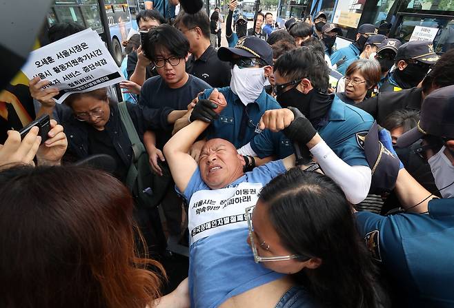 전국장애인차별철폐연대(전장연) 회원들이 17일 오후 서울 종로구 혜화동로터리 버스 정류장에서 전장연 탄압 중단을 촉구하며 '계단 버스' 탑승을 시도했으나 경찰들에 의해 강제 하차되고 있다. /뉴스1