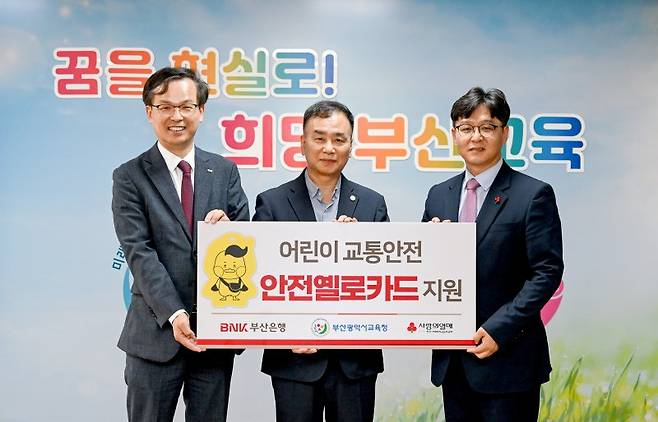 강석래 BNK부산은행 경영기획본부장과 김정태 부산시교육청 기획국장, 박선욱 부산사회복지공동모금회 사무처장(왼쪽부터)이 안전옐로카드 전달식에서 기념촬영을 하고 있다. BNK부산은행 제공