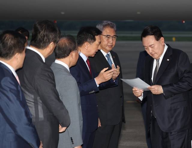리투아니아·폴란드·우크라이나 순방을 마친 윤석열 대통령이 17일 성남 서울공항을 통해 귀국해 국민의힘 김기현 대표가 준비한 자료를 보며 박진 외교부 장관 등과 대화하고 있다. 연합뉴스