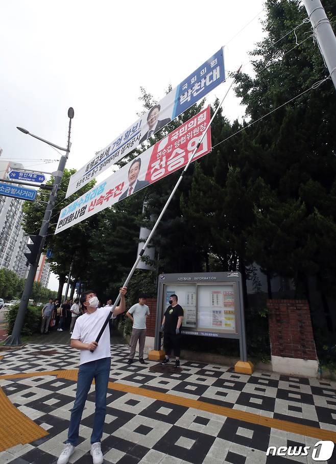 인천시 연수구 관계자가 12일 인천시 연수구 동춘동의 거리에 걸린 정당현수막을 철거하고 있다. 인천시는 지난 8일 정당현수막을 규제하는 내용의 '옥외광고물 조례개정안'을 시행하고 11일까지 계도·홍보기간을 거쳐 12일부터 본격적인 단속을 시작했다. 2023.7.12/뉴스1 ⓒ News1 정진욱 기자