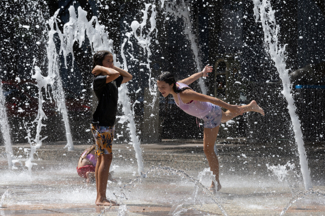 18일 미국 텍사스주 휴스턴 디스커버리 그린파크의 분수에서 10대 자매가 더위를 피해 물놀이를 하고 있다. AFP 로이터 연합뉴스