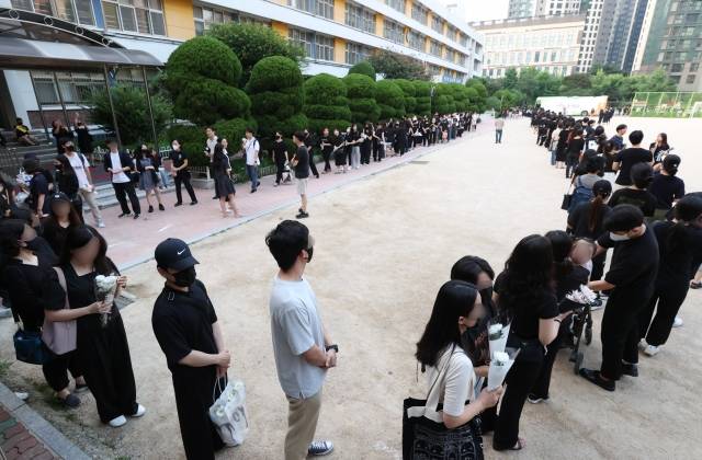 20일 오후 서울 서초구 서이초등학교에 마련된 임시 추모공간에서 추모객들이 고인이 된 교사 A씨를 추모하기 위해 기다리고 있다. 연합뉴스