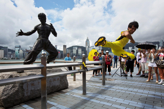 HONGKONG-BRUCE LEE/ANNIVERSARY <YONHAP NO-4216> (REUTERS) 지난 2013년 7월 20일 홍콩 해변에 있는 쿵푸 전설 이소룡 동상 앞에서 중국 배우 메이 지용이 플라잉 킥을 선보이고 있다. 로이터연합뉴스