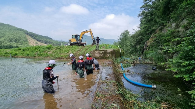 한국농어촌공사 전남지역본부 장흥지사 직원들이 장흥 오도저수지 물넘이 시설에 부유물을 제거하고 사이펀 시설을 설치하고 있다.