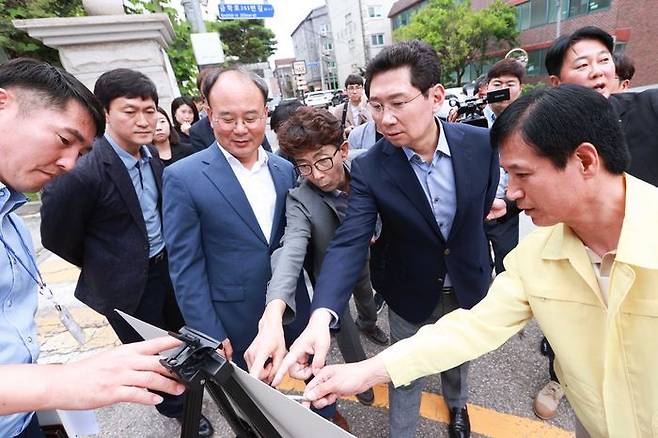 이상일 용인특례시장(오른쪽에서 두 번째)과 LH관계자, 학교 관계자 등이 현장을 살펴보며 통학로 해결방안을 논의하고 있다. ⓒ용인시 제공