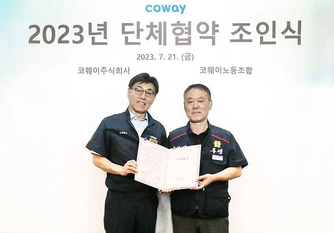 김동화 코웨이 생산본부장(왼쪽)이 지난 21일 충청남도 공주시 유구공장에서 열린 ‘2023년 임금 및 단체협약 조인식’에서 임재환 생산 코웨이노동조합 위원장과 함께 협약서에 서명한 뒤 기념 촬영하고 있다. 코웨이 제공.