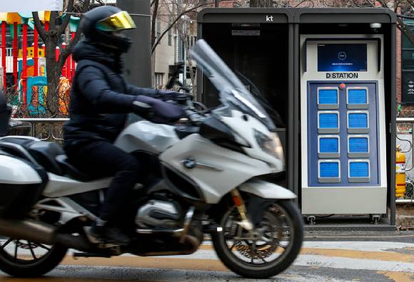 서울시내에 위치한 전기 오토바이 배터리 교환소 앞을 오토바이가 지나가고 있다. 사진은 기사와 무관 [사진=뉴시스]