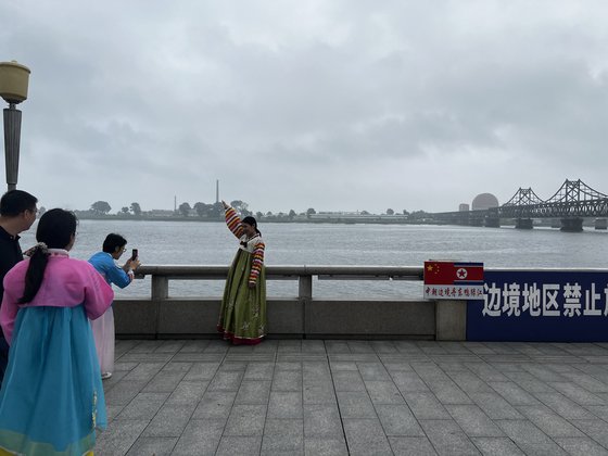 지난 14일 중국 단둥의 압록강변에서 중국 관광객이 한복을 입고 압록강 철교를 배경으로 기념사진을 찍고 있다. 단둥=신경진 특파원