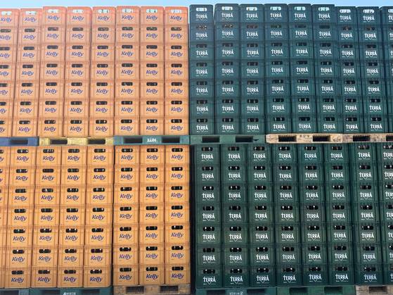 Plastic boxes filled with Kelly beer bottles, left, and Terra bottles are stocked at the outdoor storage area of Hitejinro's Gangwon Brewery. [SEO JI-EUN]
