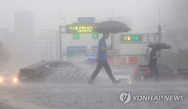 지난 13일 비가 쏟아지는 서울 여의대로 횡단보도 위로 우산을 쓴 시민들이 지나고 있다. [연합뉴스 자료사진]