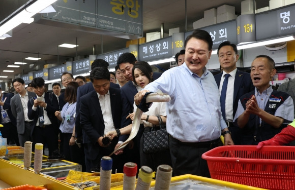 윤석열 대통령이 27일 부산 중구 자갈치시장에서 장어를 직접 손으로 잡아 보며 즐거워 하고 있다.  부산 연합뉴스