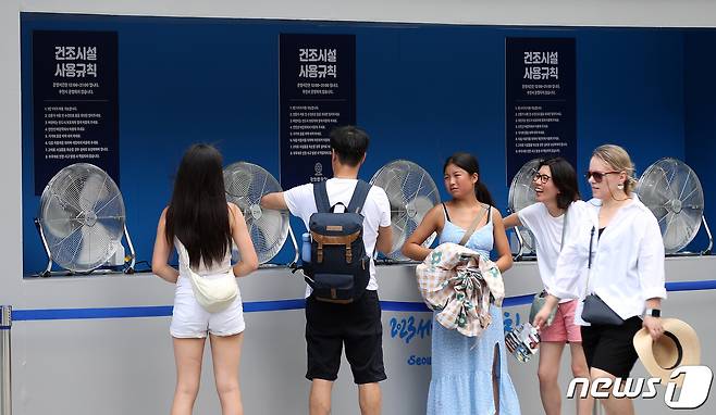 서울 광화문광장에 설치된 건조시설에서 외국인 관광객들이 땀에 젖은 옷을 말리고 있다. 2023.7.26/뉴스1 ⓒ News1