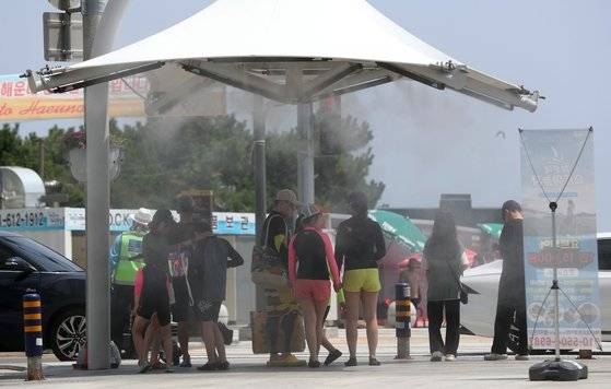 부산지역에 폭염경보가 발효 중인 28일 오후 부산 해운대구 구남로에 쿨링포그(안개형 냉각수)가 가동돼 시민들과 관광객들의 더위를 식혀주고 있다. [뉴스1]