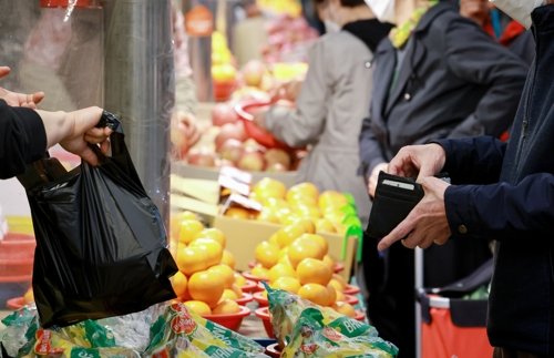 한 소비자가 지갑을 열어 계산하고 있는 모습. [사진 제공 = 연합뉴스]