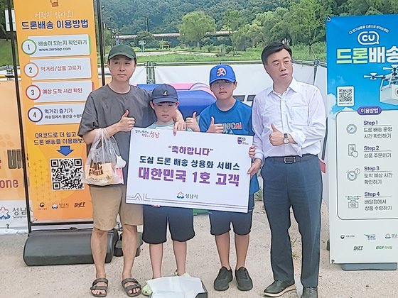 성남시 도심 드론 배송 상용화 서비스의 대한민국 1호 고객이 된 이신구(43)씨와 이씨 아들 동엽(10)군, 조카 조동준(12)군이 신상진 성남시장의 축하를 받고 있다. 손성배 기자