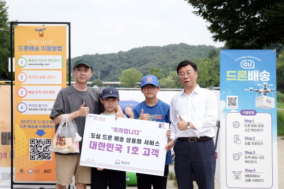 신상진(왼쪽 4번째) 시장이 1일  오전 국내 첫 유료 드론 배송 서비스 1호 주문 고객 이신구씨 가족에게 기념품을 전달하고 사진을 찍고 있다.  성남시 제공