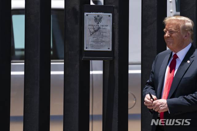 [산루이스=AP/뉴시스]도널드 트럼프 미국 대통령이 23일(현지시간) 미 애리조나주 산루이스의 국경장벽을 방문해 장벽에 서명 후 미소짓고 있다. 2020.06.24.