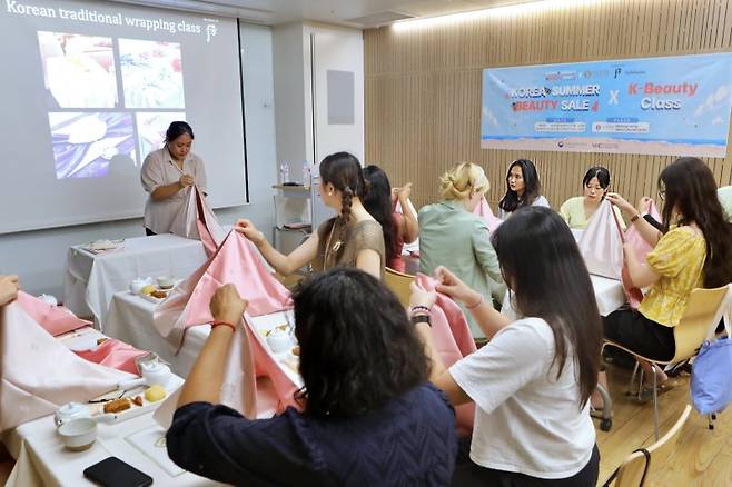 지난 3일 롯데백화점 본점에서 진행된 K-뷰티 클래스 전경. 외국인들이 한국 전통 문양의 보자기를 활용한 '보자기 아트'를 체험하고있다.