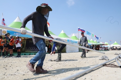 세계스카우트연맹이 잼버리 대회가 열리는 부안군에서 조기 철수를 결정한 6일, 행사 관계자들이 세계 각국 대표단이 문화를 홍보하는 부스 앞에 설치된 그늘막을 해체하고 있다. 연합뉴스