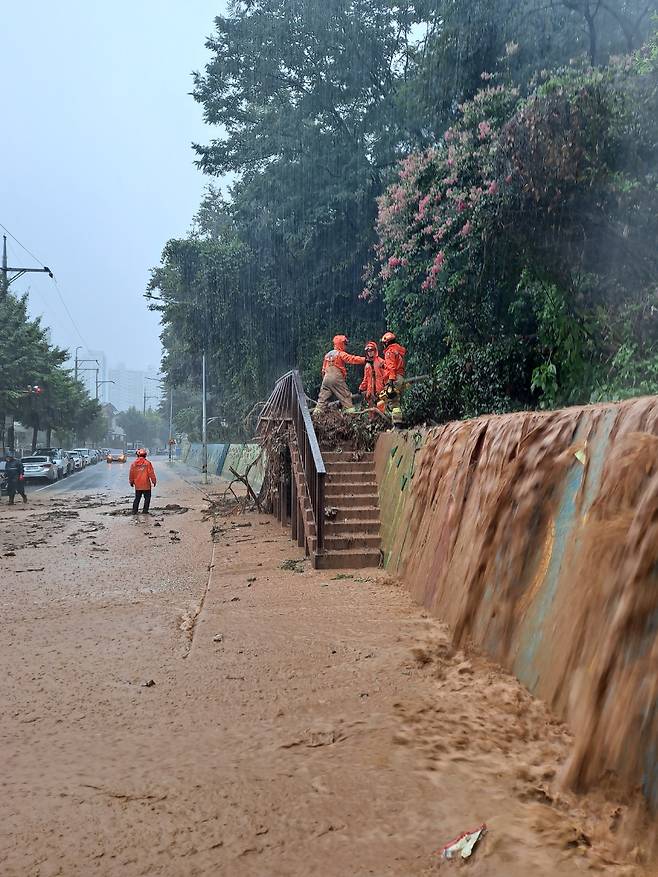 8.10.(목) 오전, 경남 창원시 성산구 상남동에서 산에서 흙탕물이 내려온다는 신고를 받고 출동한 소방대원들이 주변 잡목과 토사를 제거하고 있다.