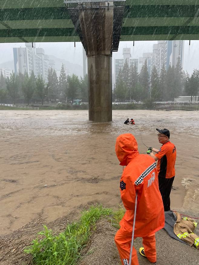 8.10.(목) 오전, 경남 창원시 마산회원구 내서읍 광려천 인근에서 불어난 물로 고립된 여성을 출동한 소방대원이 구조하고 있다.