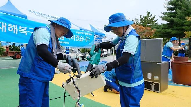 삼성전자서비스가 14일 강원도 고성군 거진청소년문화의집에 이동식 서비스센터를 설치하고 침수된 가전제품 세척, 점검, 수리 등 수해 복구 특별서비스를 하는 모습.[삼성전자서비스 제공]