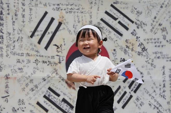 15일 오후 서울 종로구 북인사마당을 찾은 어린이가 한국광복군 서명문 태극기 앞에서 밝은 표정을 짓고 있다. 