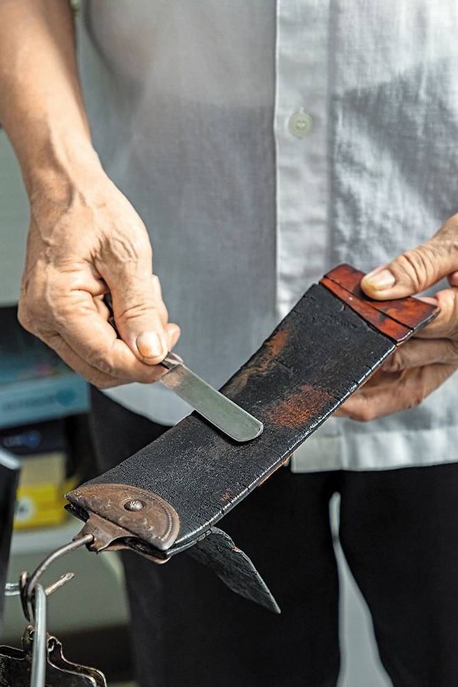 이남열 이발사가 면도칼을 말가죽 피대에 긁어 날을 세우고 있다. 피대는 아버지가 1950년대 미군 PX에서 구입해서 쓰다가 물려준 것이다. /장은주 영상미디어 객원기자