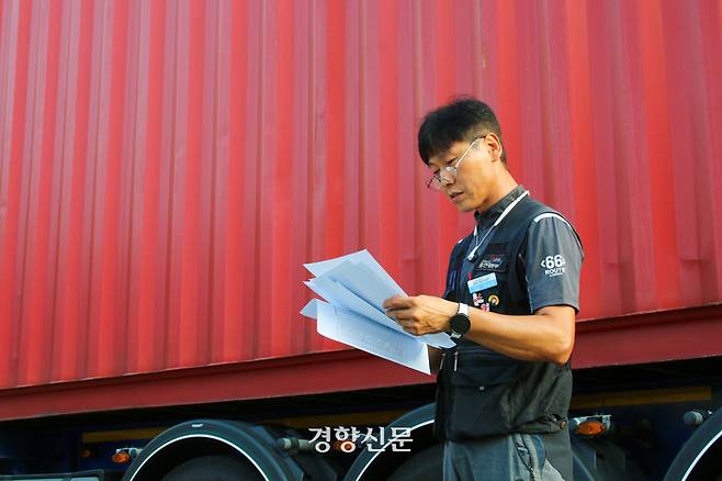 지난 17일 오후 경기 의왕 내륙컨테이너기지(ICD)에서 화물기사 허남행씨(52)가 자신의 화물차 컨테이너 옆에서 거래명세서를 살펴보고 있다. 조해람 기자