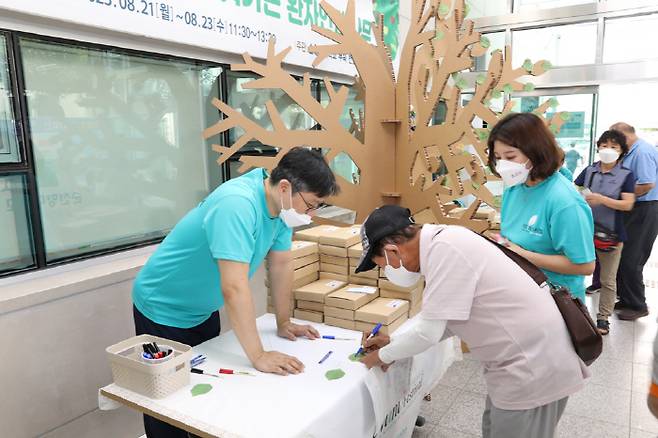 순천향대 천안병원이 21일 병원 외래진료관 입구에서 의료질 향상과 환자안전문화 조성을 위한 박하페스티벌을 개최했다. 박하나무에 붙이기 위해 외래환자가 환자안전에 대한 바람을 박하잎 모양 포스트잇에 적고 있다.