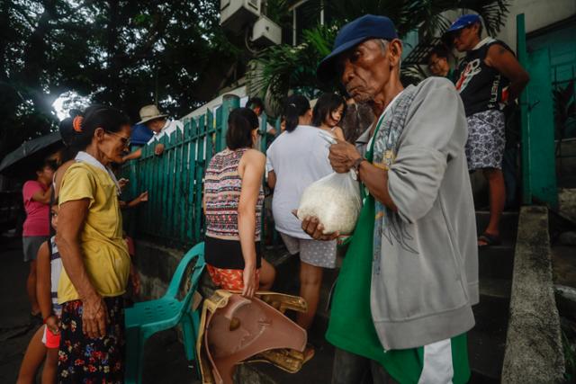 지난 6월 필리핀 마닐라에서 시민들이 쌀을 사기 위해 길게 줄을 서 있다. 기후변화와 이에 따른 쌀 생산량 감소, 인도 등 주요 수출국의 수출 제한으로 쌀 대부분을 외국에서 수입하는 필리핀이 타격을 입고 있다. 마닐라=EPA 연합뉴스